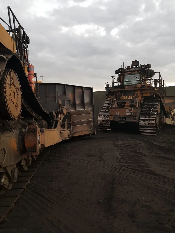 Two dozers parked on a mine site under a cloudy sky