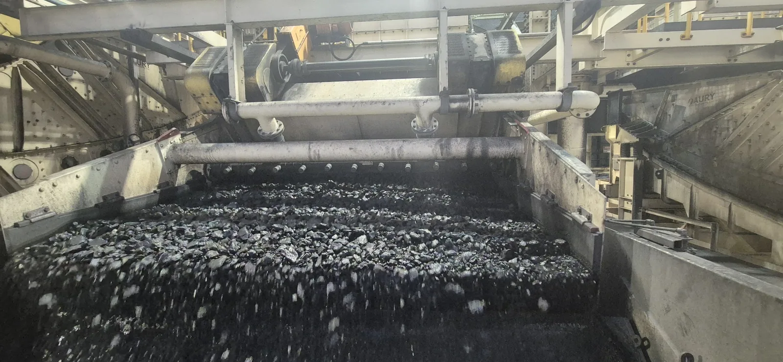 Coal running across a vibrating screen deck under spray bars in a coal preparation plant